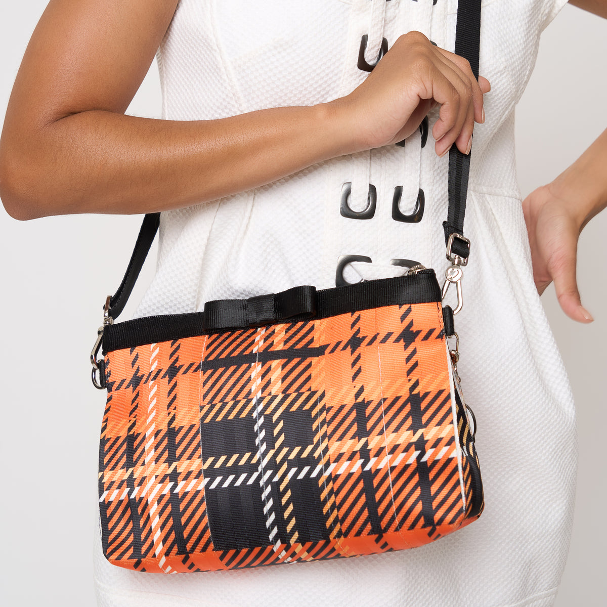 Model carrying Bow Clutch in orange tartan with adjustable black strap