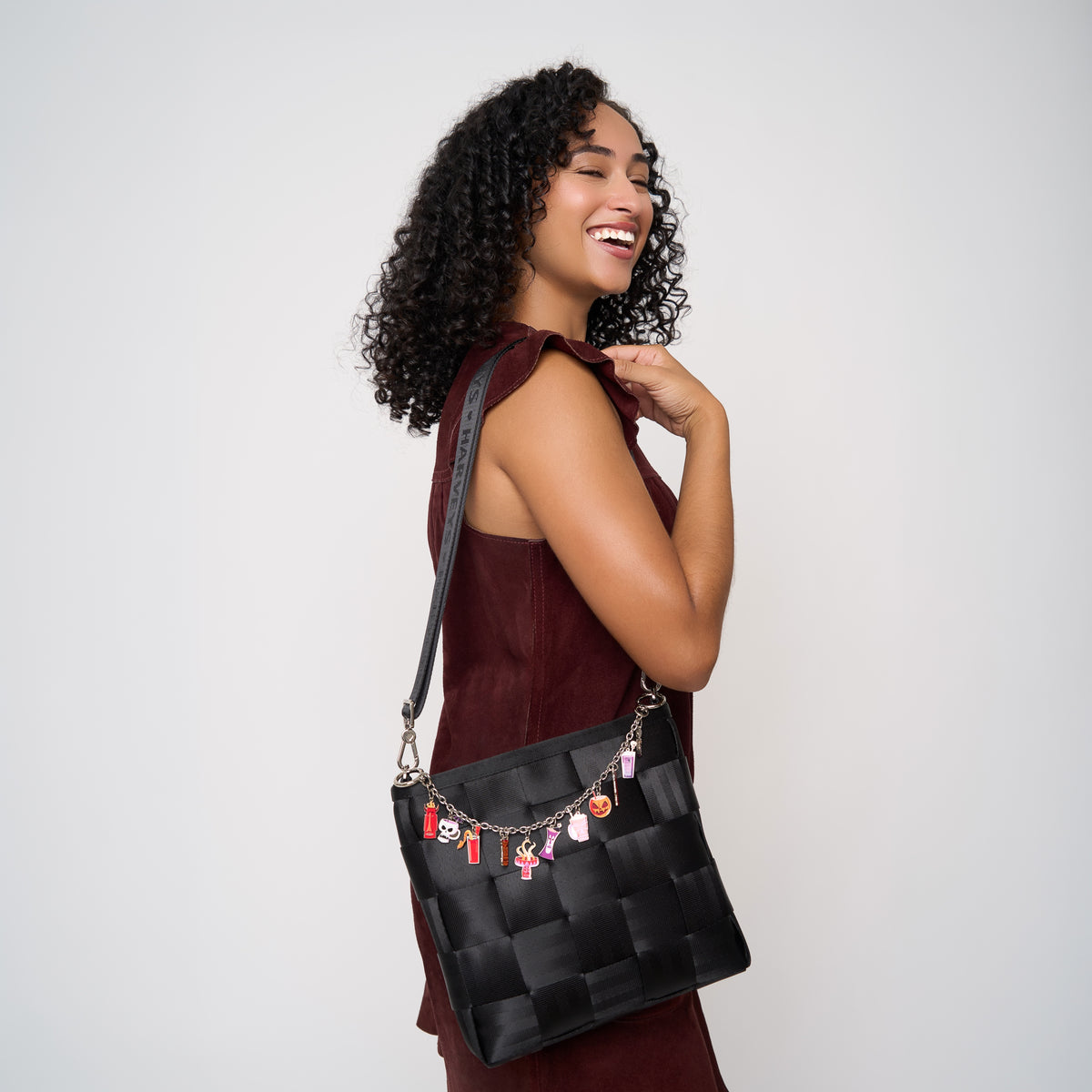Photo of model wearing a black mini messenger bag over her shoulder with Shag Spooky Cocktail bag charm attached.