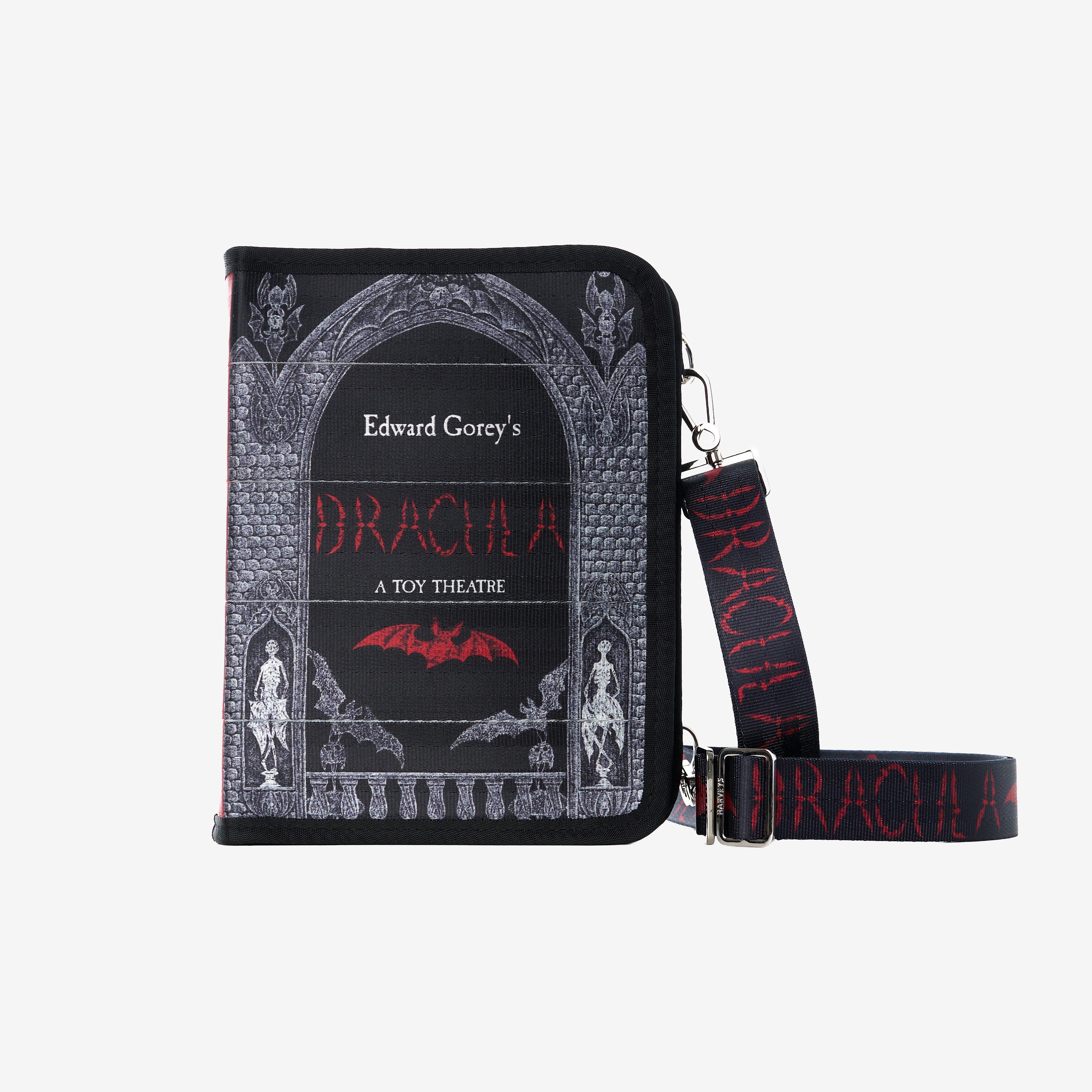 A black Crossbody handbag with an illustrated Dracula book cover design with a matching black wrist strap printed with 'Dracula' in red, shown on a light gray background