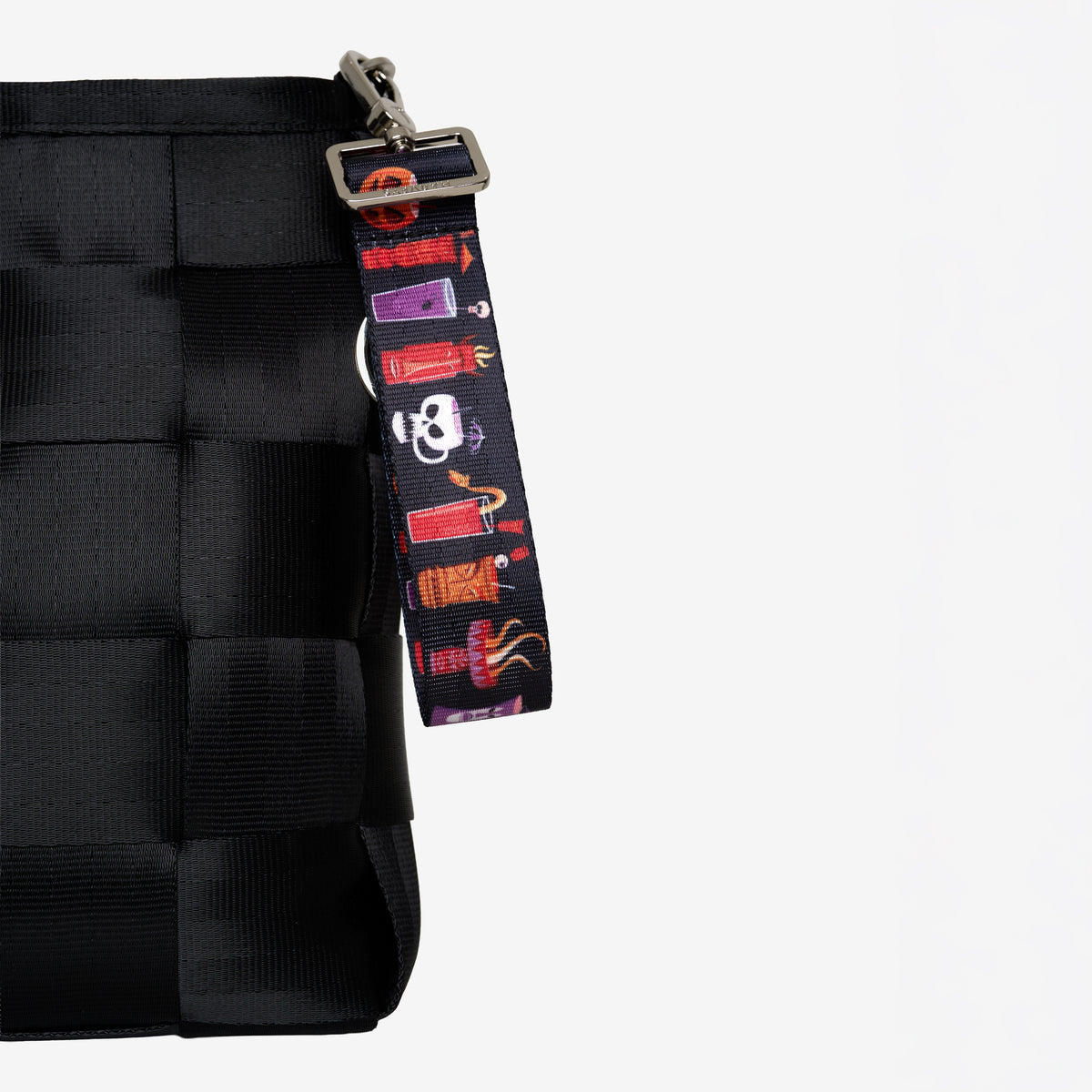 Front view of 4 panel keychain Shag Spooky Tiki Cocktail attached to black mini messenger bag