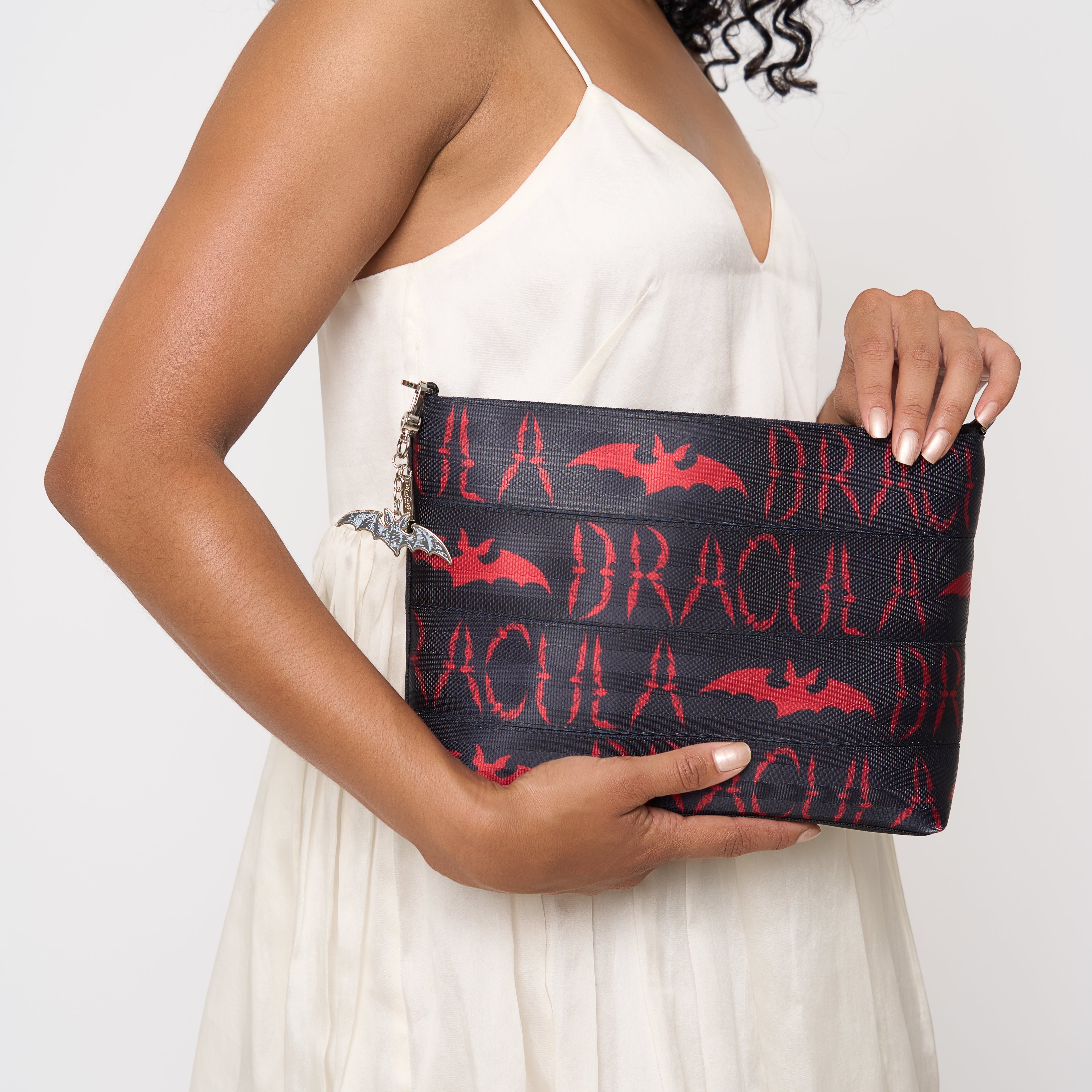 Model holding black clutch with red Dracula and bat lettering and silver bat charm