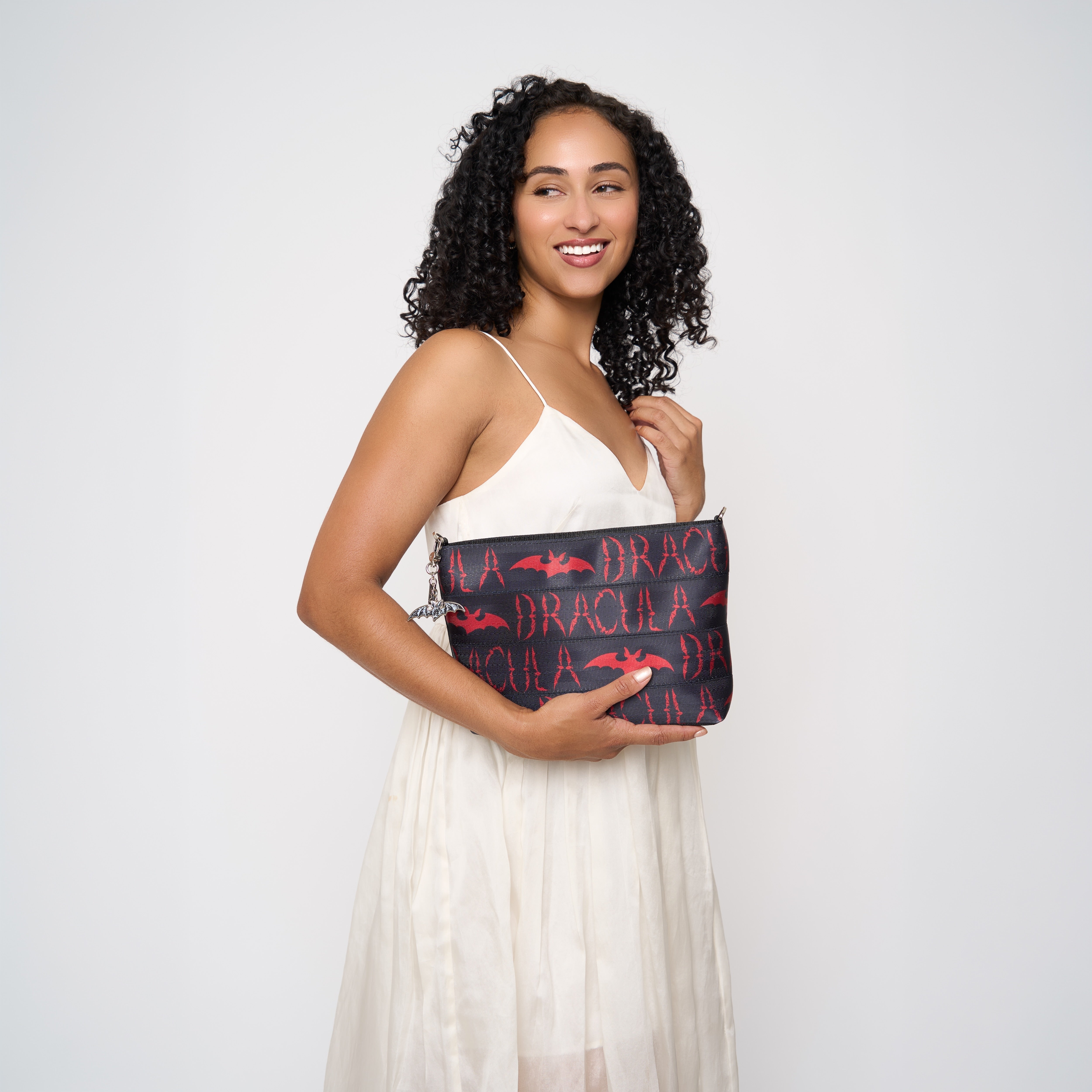 Model holding black clutch with red Dracula and bat lettering and silver bat charm