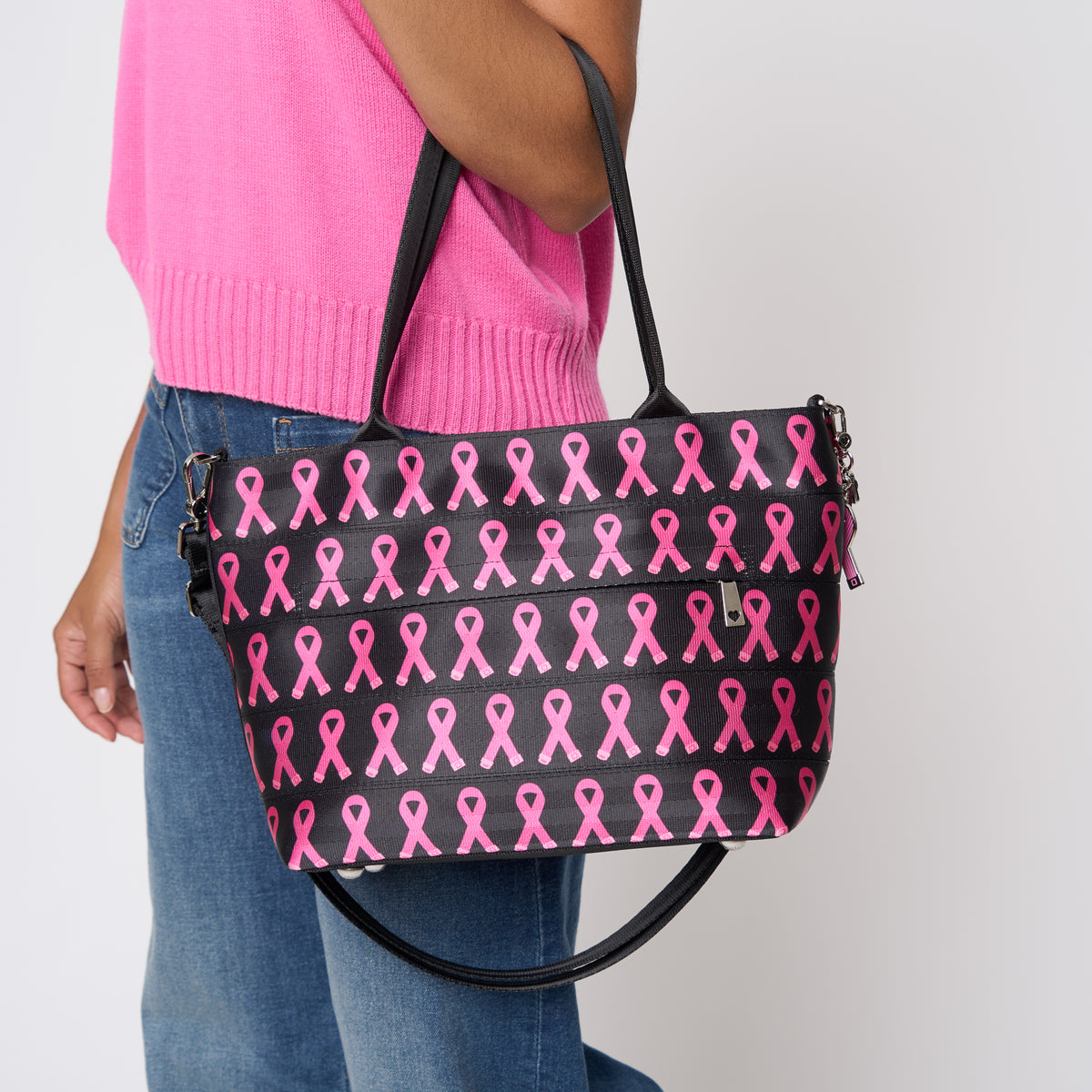 A model wearing The Pink Agenda Pink Ribbon Mini Streamline Tote