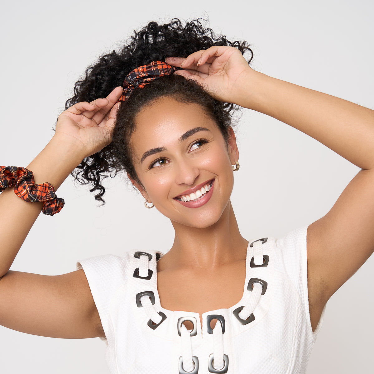 View of model wearing orange tartan scrunchies in her hair and on her wrist