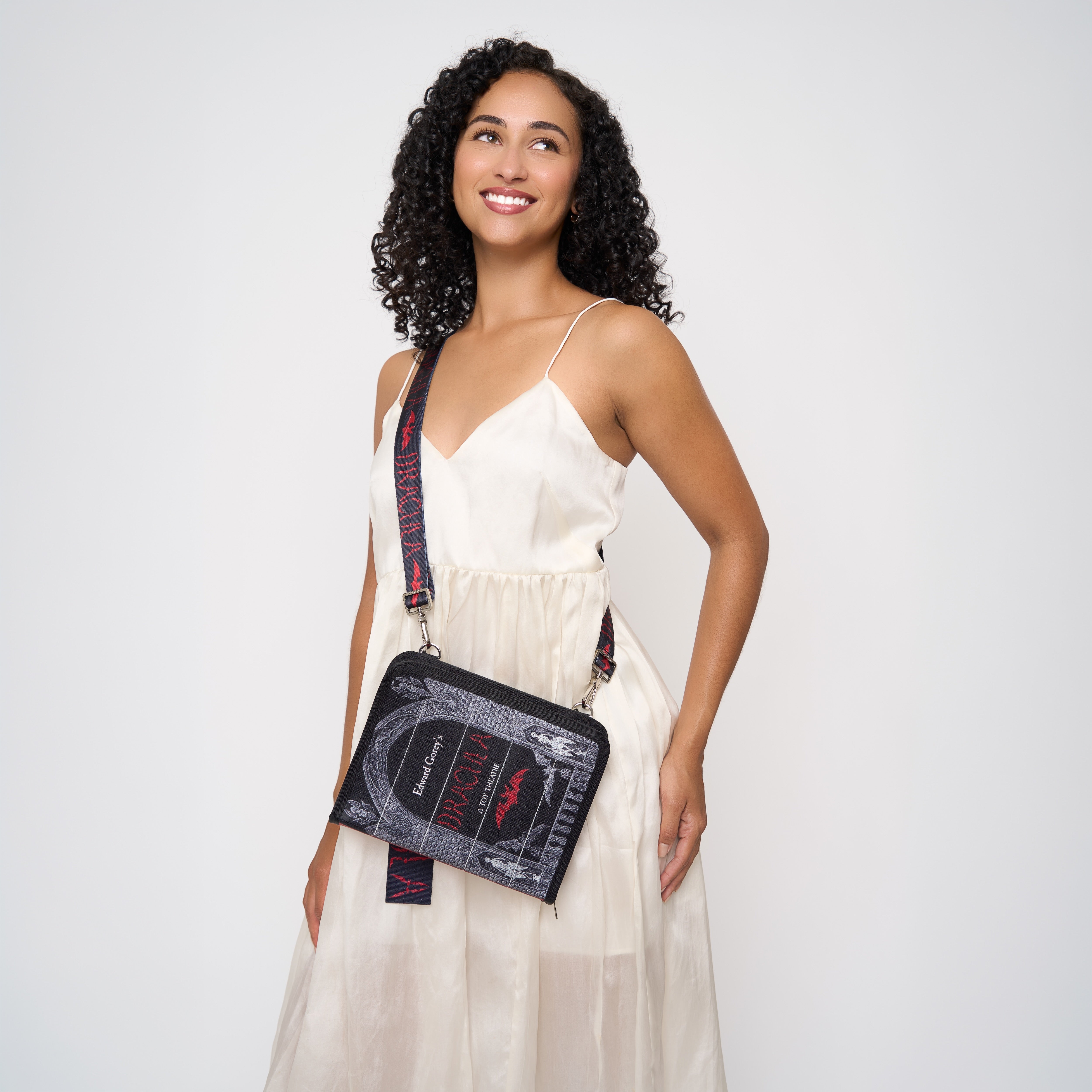 Model wearing black crossbody back shaped like book with Dracula strap