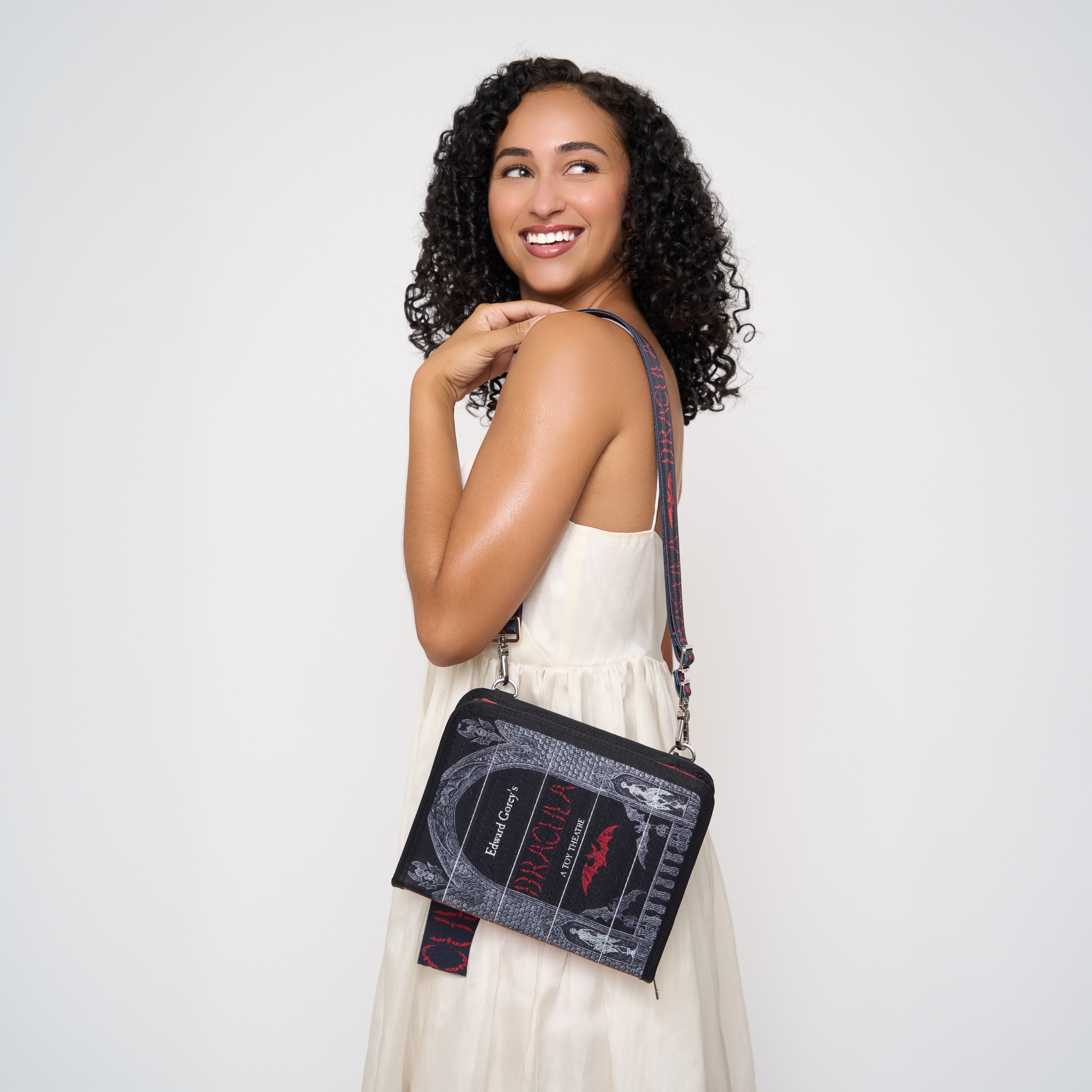 Model holding a crossbody book shaped bag with Dracula written on front