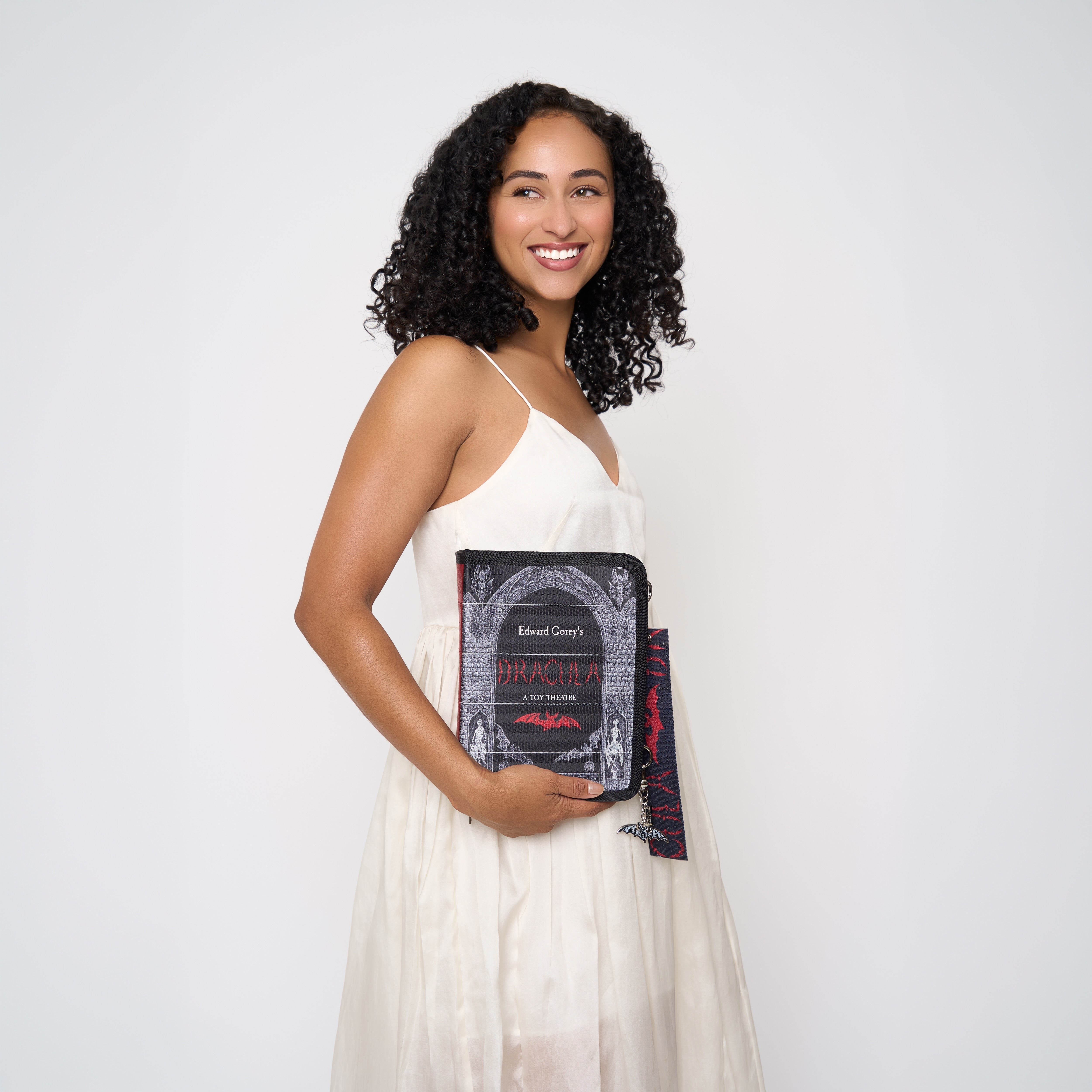 Model wearing black crossbody back shaped like book with Dracula strap