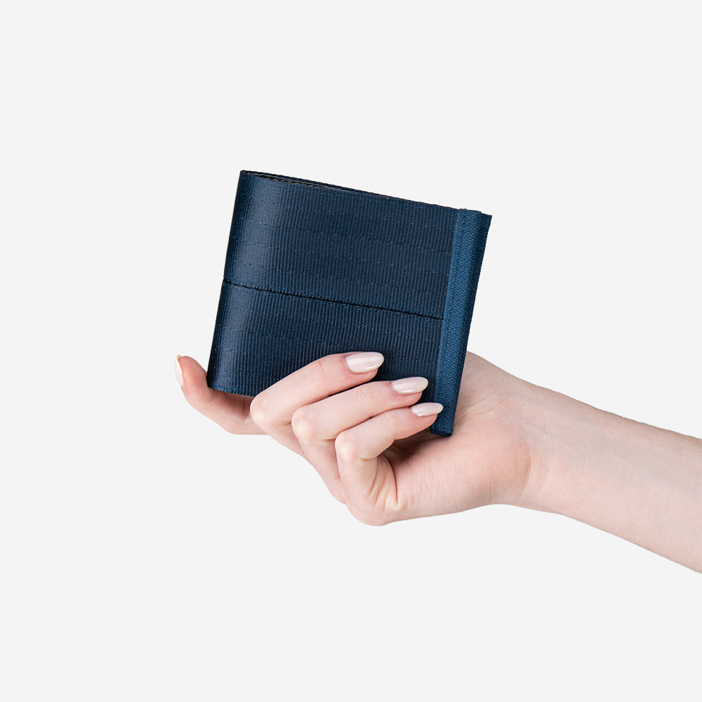 A Billfold in Indigo being held in a models hand