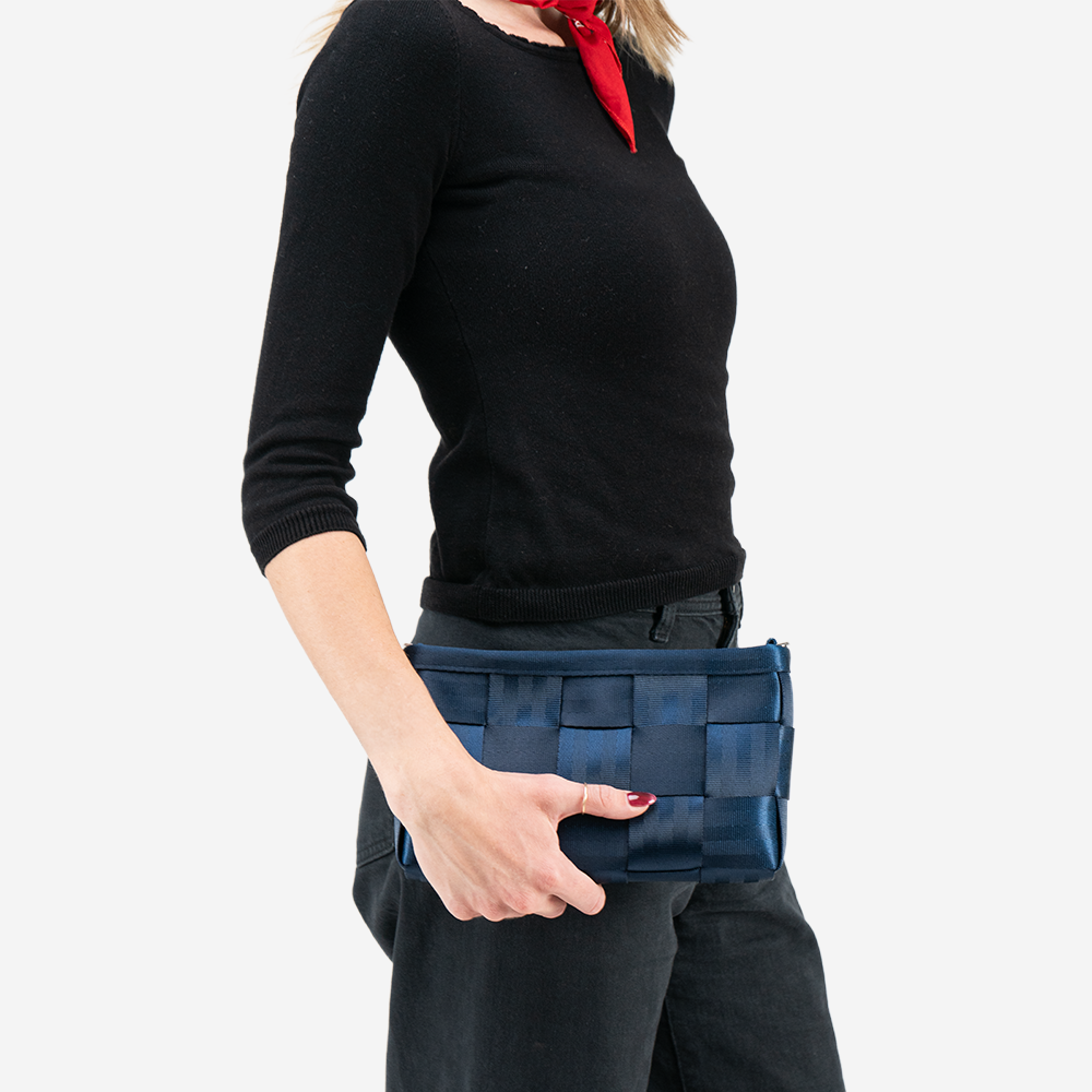 A Convertible Clutch in Indigo being held in a models hand