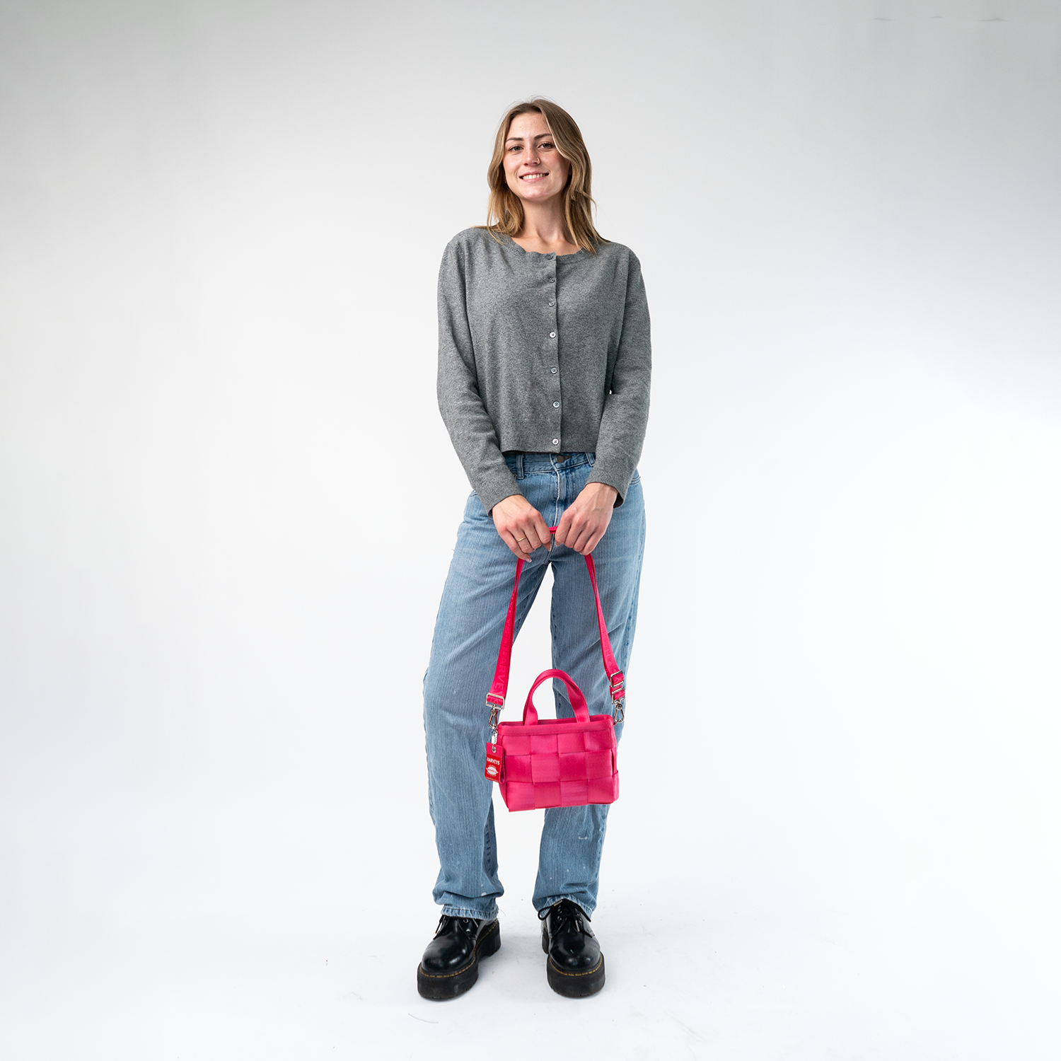 A Woven Petite Tote in Melon being held in a Model's hands