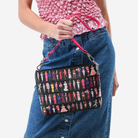 The Barbie Through The Eras Medium Convertible Clutch being held by a model