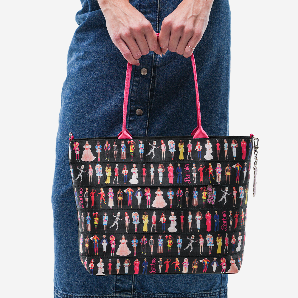 The Barbie Through The Eras Medium Streamline Tote being held by a model