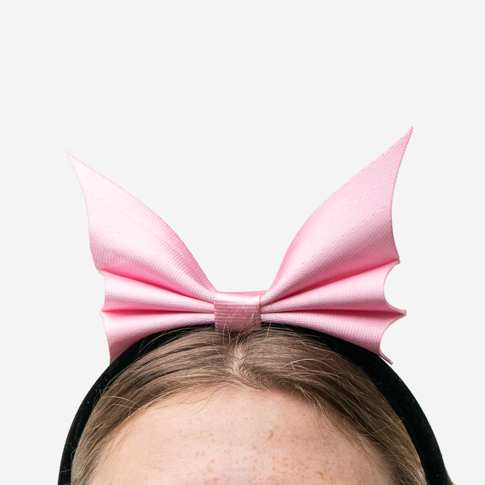A Bat Headband in Petal Pink being worn by a model
