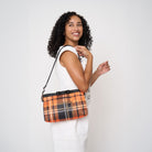 Model carrying Bow Clutch in orange tartan with adjustable black strap