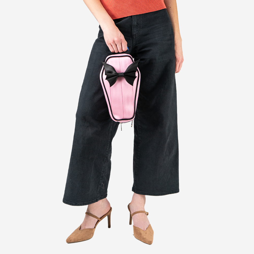 A Petal Pink Coffin Convertible Crossbody being held by a model.