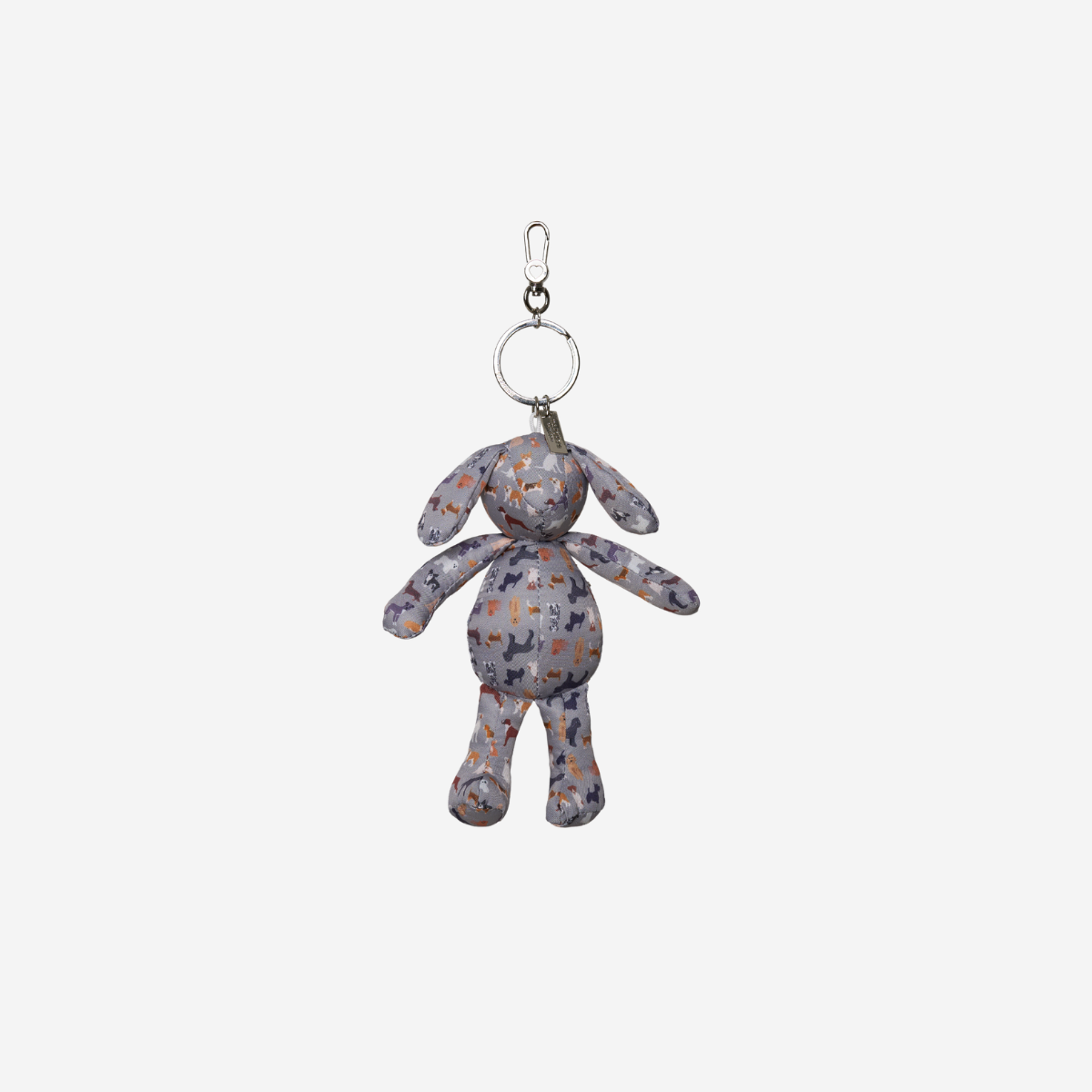 A small plush dog keychain charm with a gray, white, and orange patterned fabric body, attached to a silver metal split ring and clip, shown against a plain light gray background.
