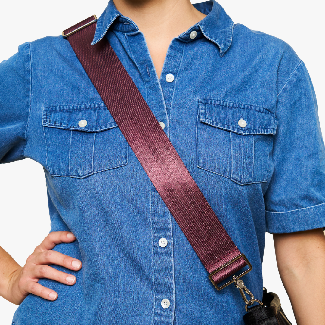 A close-up of a person wearing a blue denim shirt, showing a 5 Panel Click n Carry  shoulder strap diagonally across the chest.