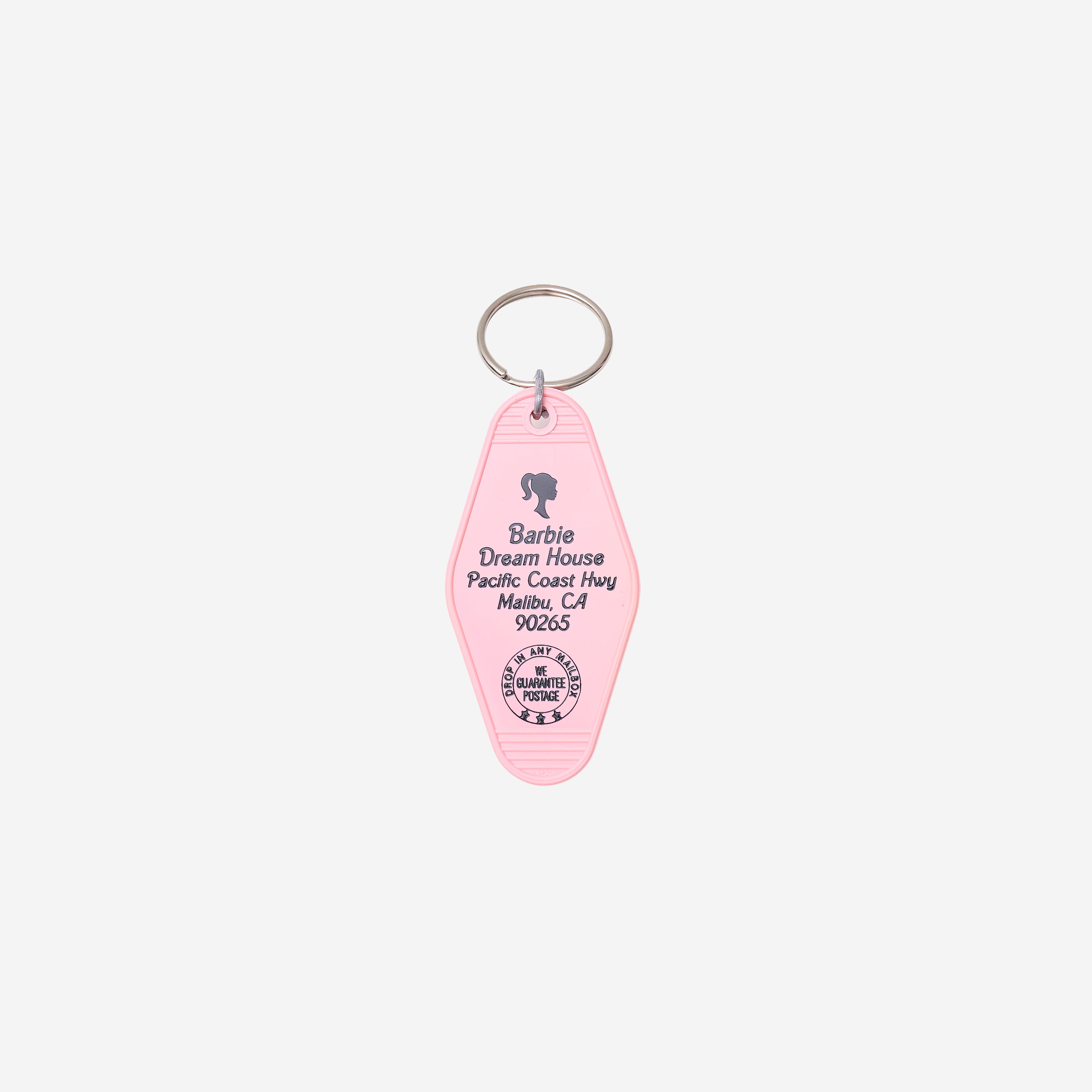 A pink key tag featuring the Barbie Dream House address printed in black, attached to a silver metal split ring, on a light gray background.