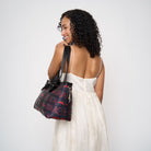 model holding large bat tote over shoulder showing side view of bag with silver bat charm