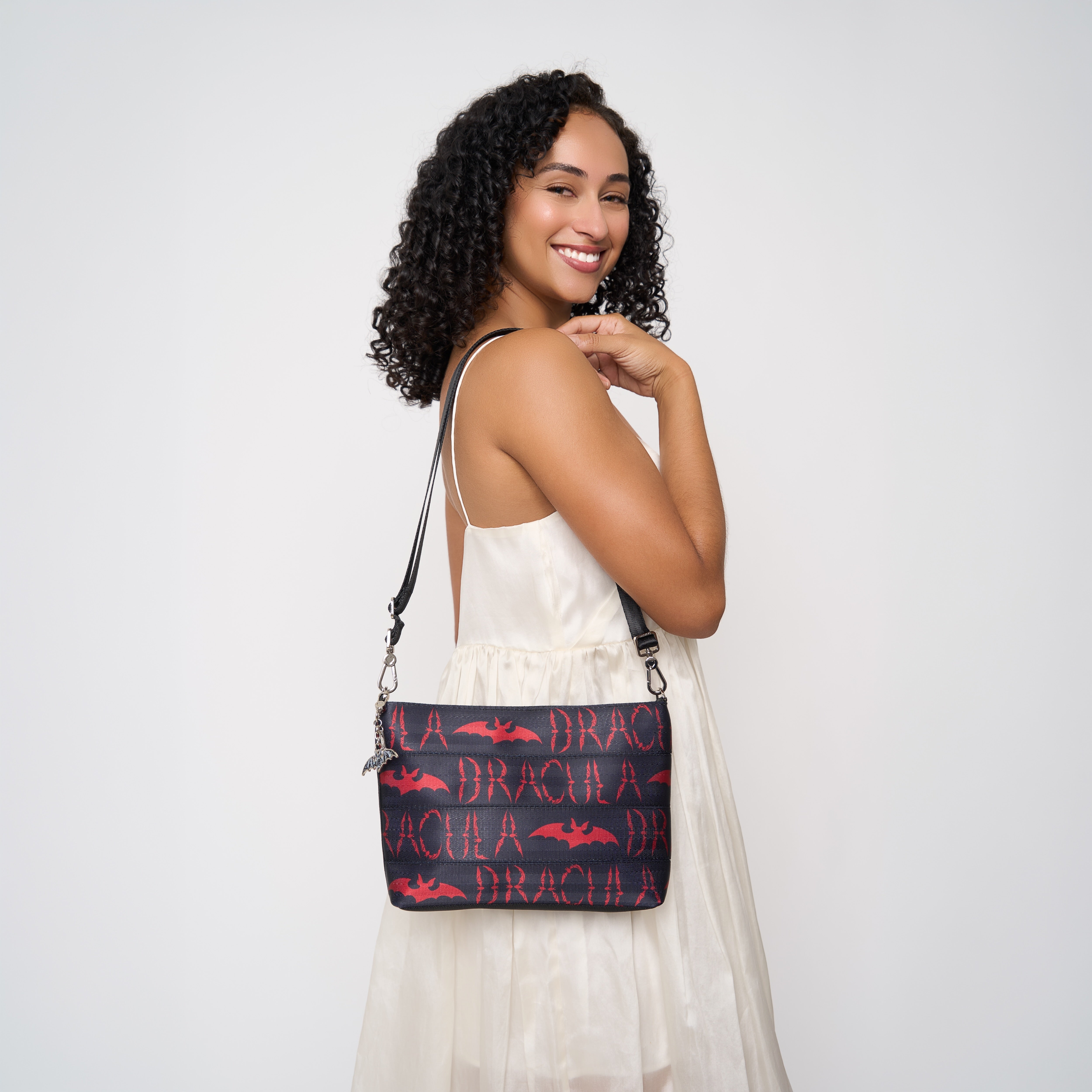Model wearing black clutch with black shoulder strap