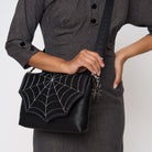 A model wearing a Black Widow Medium Foldover Crossbody Collector's Series