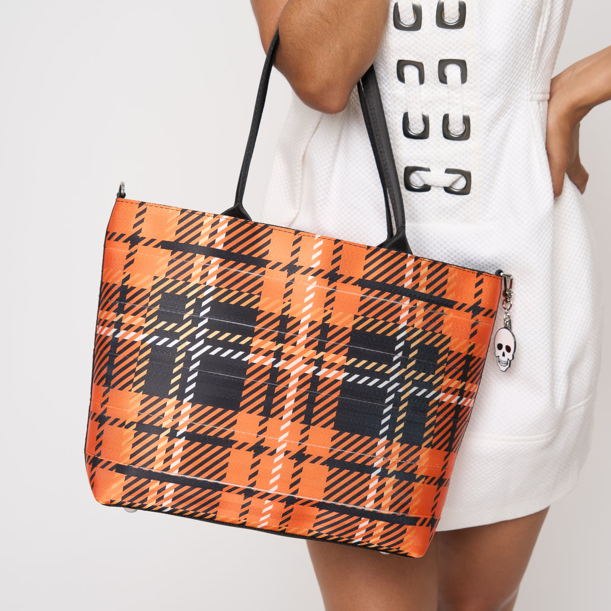 Close up of model carrying Medium Streamline Tote in orange tartan