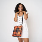 Model carrying Medium Streamline Tote in orange tartan with adjustable black strap