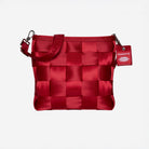 A red woven seatbelt shoulder bag with a matching strap and a red hanging tag that reads HARVEYS, shown against a plain light gray background.