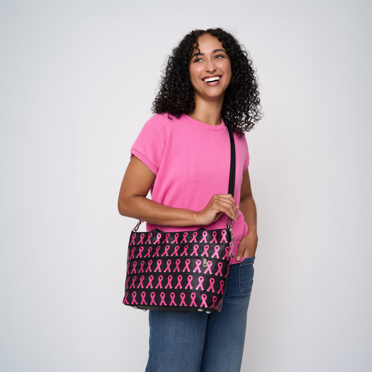 A model wearing The Pink Agenda Pink Ribbon Mini Streamline Tote