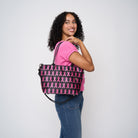 A model wearing The Pink Agenda Pink Ribbon Mini Streamline Tote