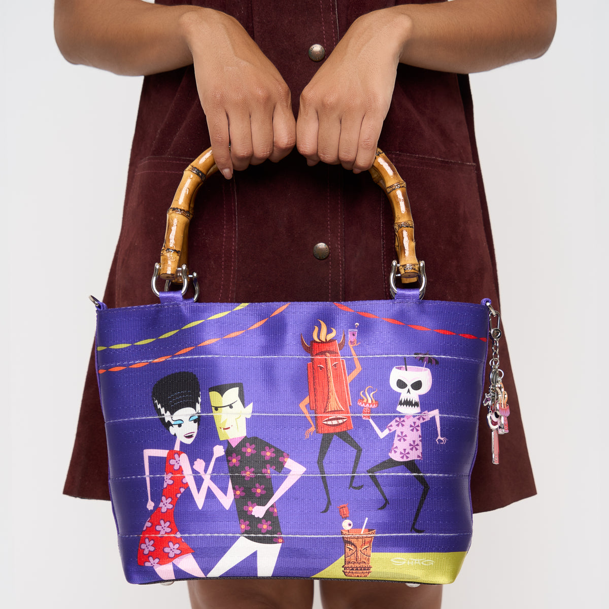 Model holding Mini Streamline Tote Shag Tiki Dance Party by the bamboo handles