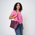A model wearing The Pink Agenda Pink Ribbon Mini Streamline Tote