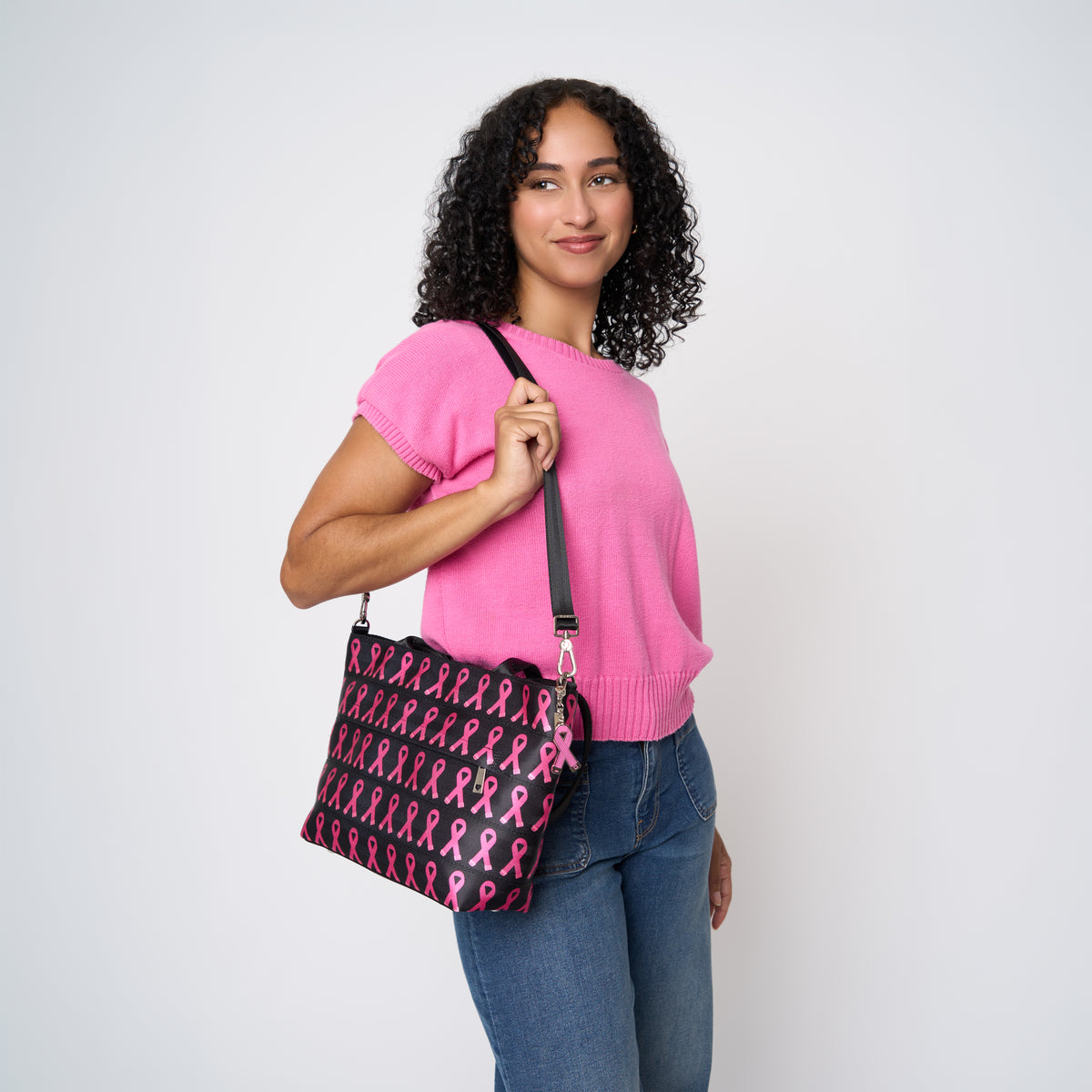 A model wearing The Pink Agenda Pink Ribbon Mini Streamline Tote
