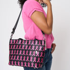 A model wearing The Pink Agenda Pink Ribbon Mini Streamline Tote
