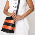 Close up of model using adjustable strap to wear Rosie tote in Jack O'Lantern