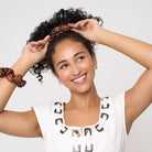 View of model wearing orange tartan scrunchies in her hair and on her wrist