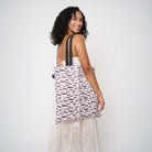 Model wearing shopper tote featuring a bat design