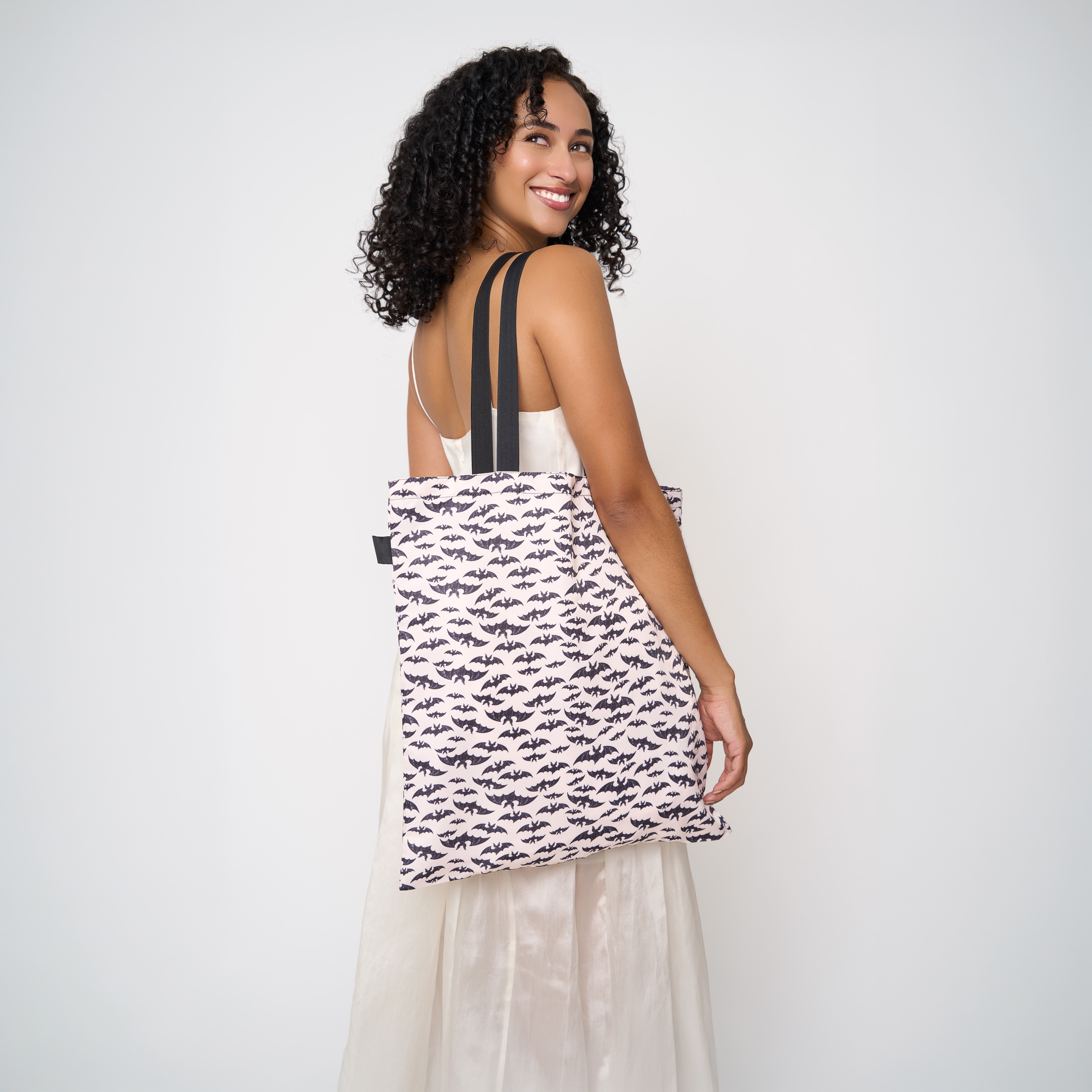 Model wearing shopper tote featuring a bat design