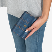 A Snap Wallet in Denim in a models hand