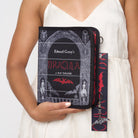 Model holding black crossbody book shaped bag