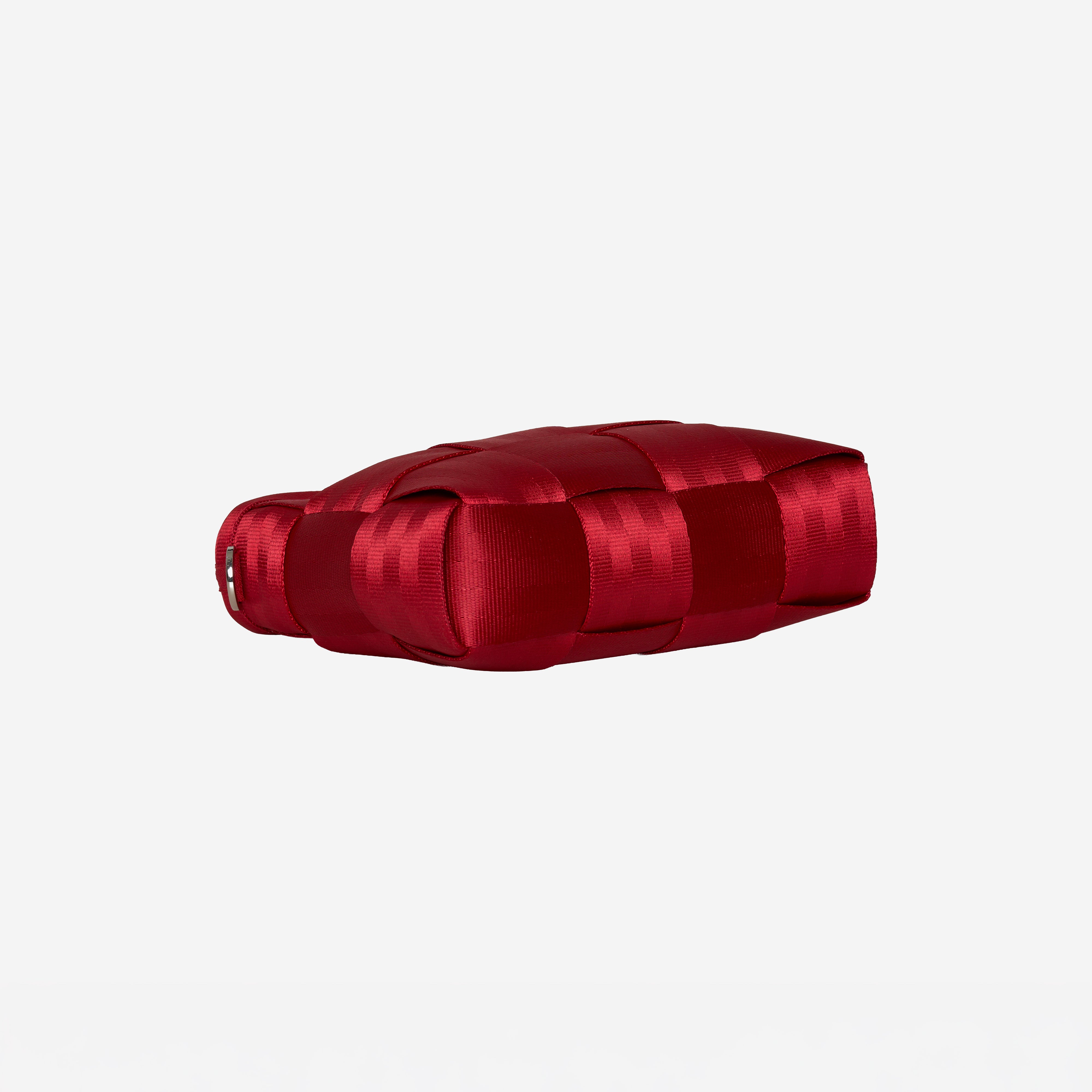 A red woven seatbelt tote  shown from a bottom profile on a light gray background.