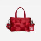 A red woven seatbelt handbag with top handles and an adjustable shoulder strap, featuring a hanging red tag with the brand name 'Harveys'.