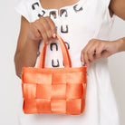 Model holding woven petite tote orange