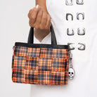 Close up of model holding woven petite tote in orange tartan 