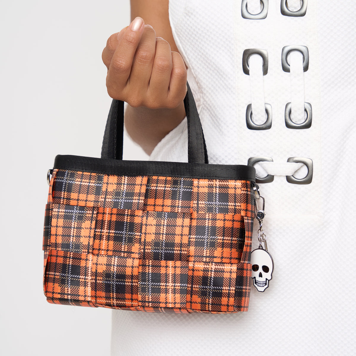 Close up of model holding woven petite tote in orange tartan 