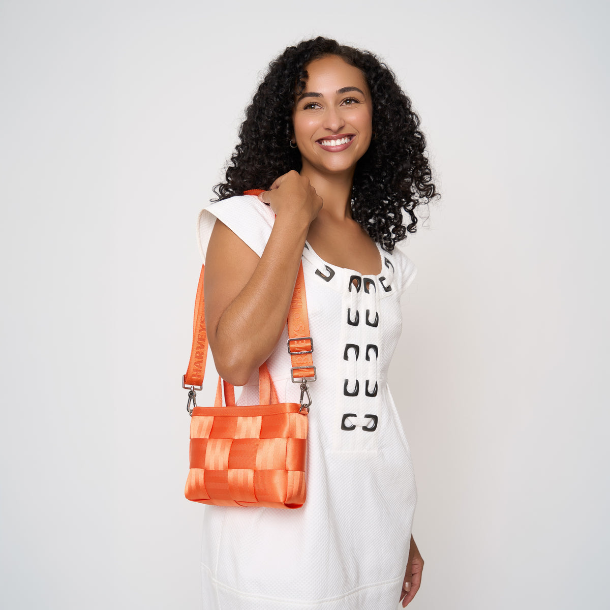 Model using adjustable strap to carry woven petite tote orange