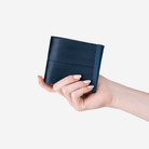 A Billfold in Indigo being held in a models hand
