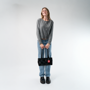 A satchel in Black in a model's hands