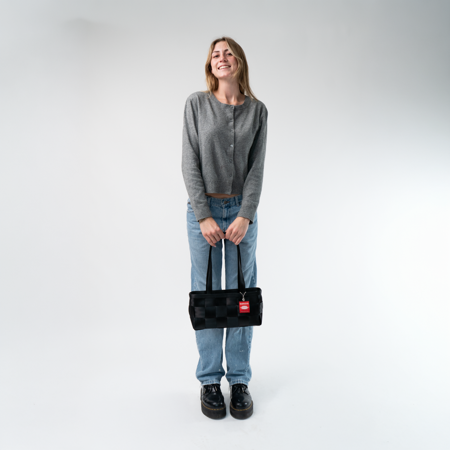 A satchel in Black in a model's hands