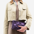 The Convertible Clutch in Blackberry being held by a model